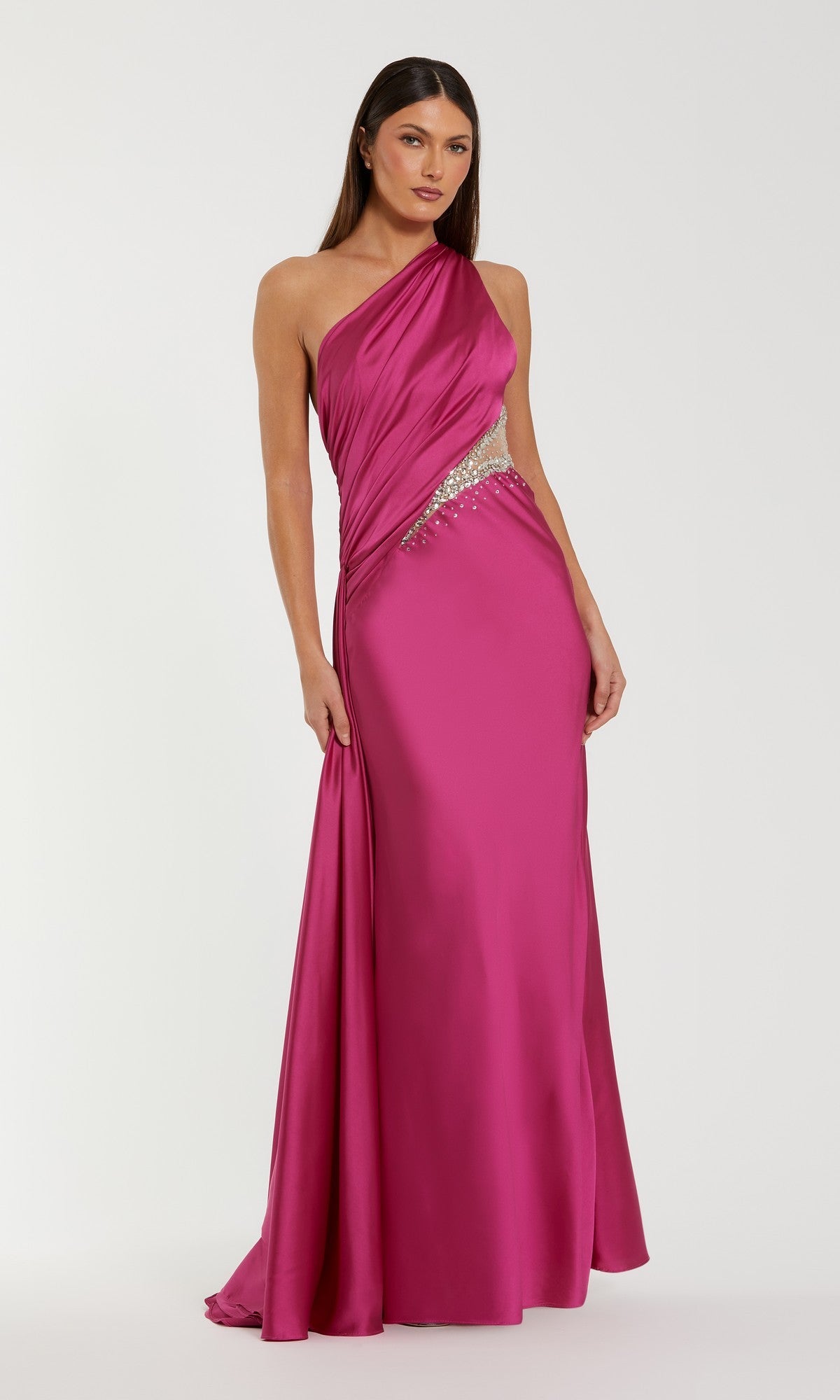A woman models the Mac Duggal 2210 Cut-Out One-Shoulder Formal Dress in bright pink, featuring a beaded waist cutout, standing against a plain white background.